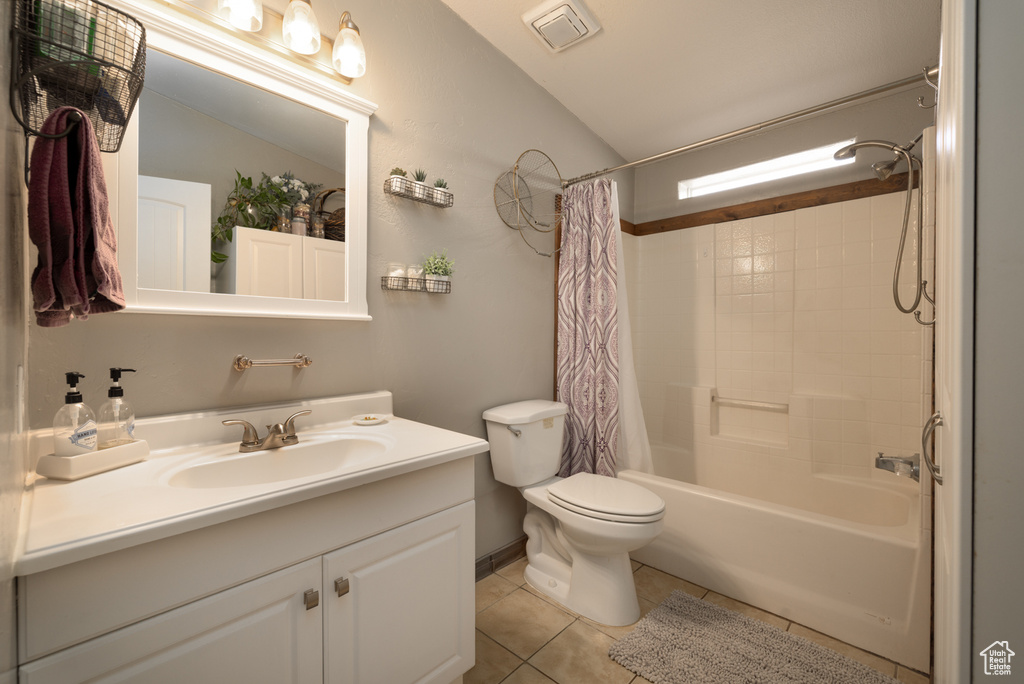 Full bathroom featuring vaulted ceiling, tile patterned flooring, vanity, toilet, and shower / bathtub combination with curtain