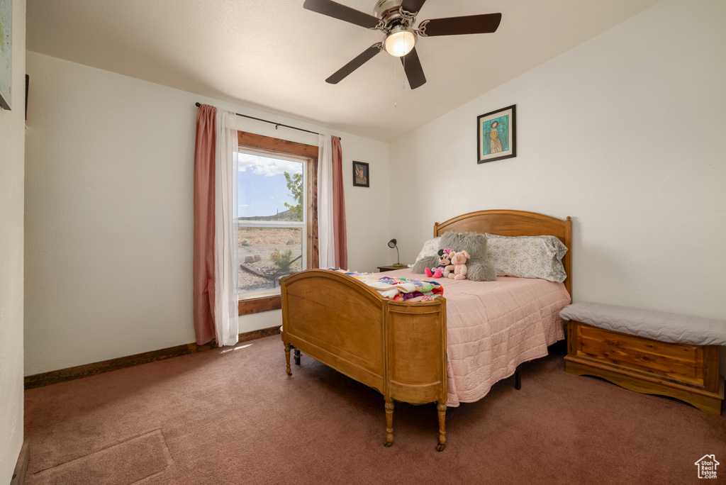 Carpeted bedroom featuring a ceiling fan and baseboards