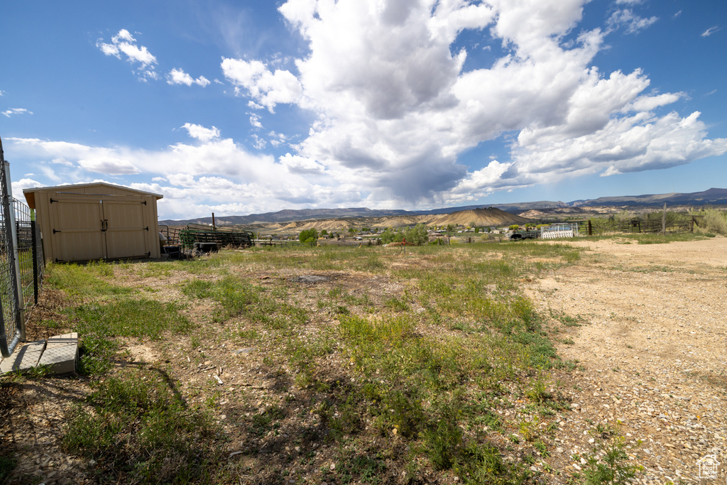 View of yard with a shed, a mountain view, fence, an outdoor structure, and a rural view