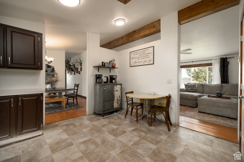 Dining room featuring beam ceiling, a chandelier, a ceiling fan, and stone finish floors