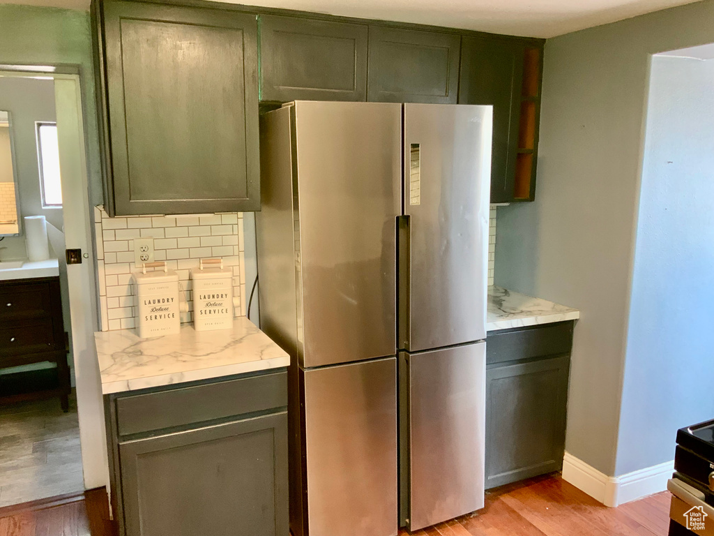 Kitchen featuring freestanding refrigerator, tasteful backsplash, light wood-type flooring, and baseboards