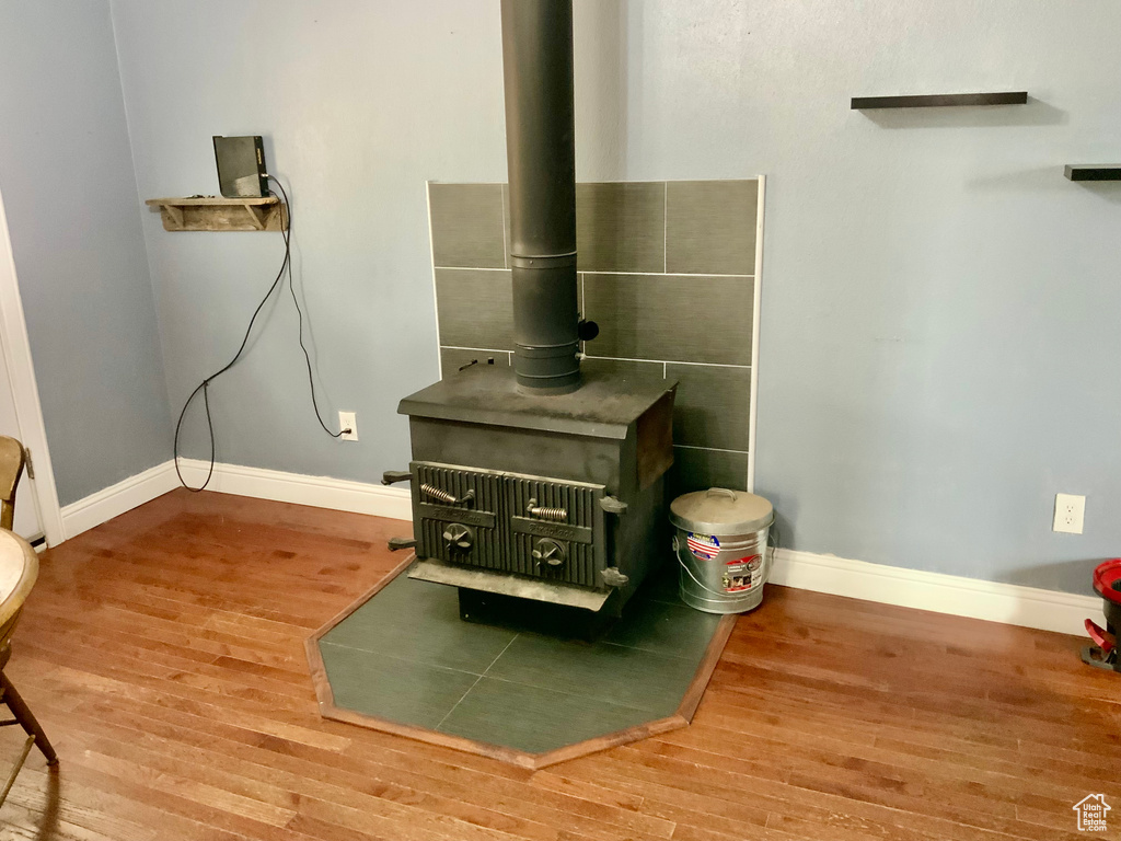 Detailed view of a wood stove, baseboards, and wood finished floors