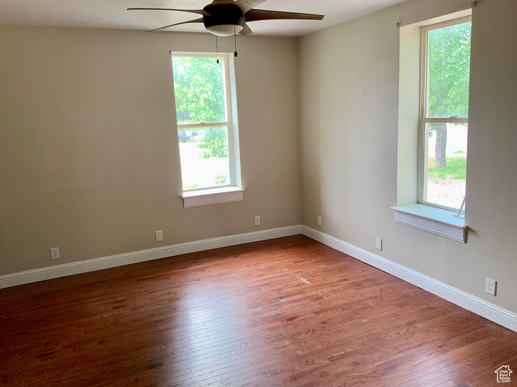 Spare room featuring ceiling fan, wood-type flooring, and baseboards