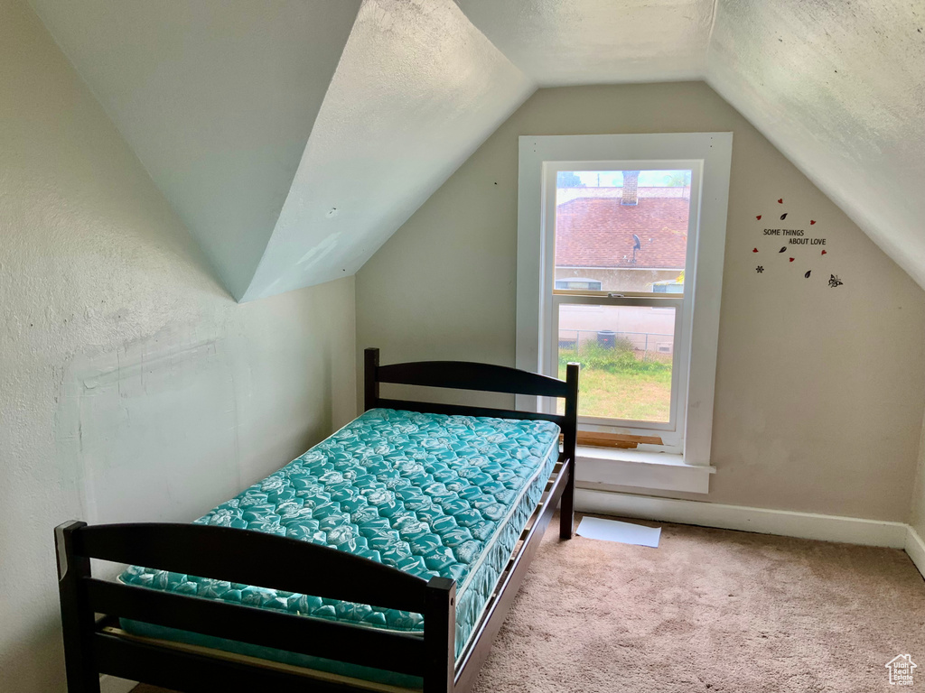 Bedroom featuring vaulted ceiling, carpet flooring, and baseboards