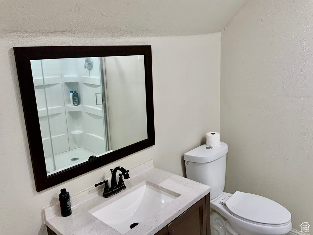 Bathroom with toilet, vanity, and an enclosed shower