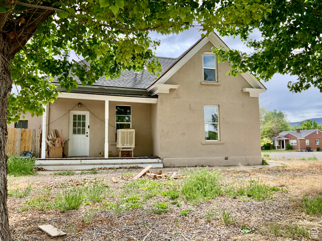 Rear view of property with roof with shingles, stucco siding, and fence