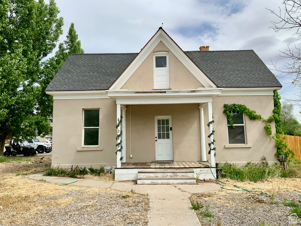 Bungalow-style home with stucco siding, roof with shingles, fence, and a chimney