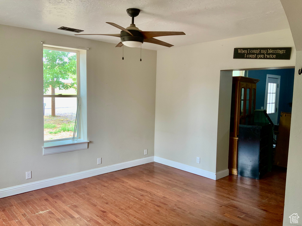 Spare room featuring wood finished floors, ceiling fan, baseboards, and a textured ceiling