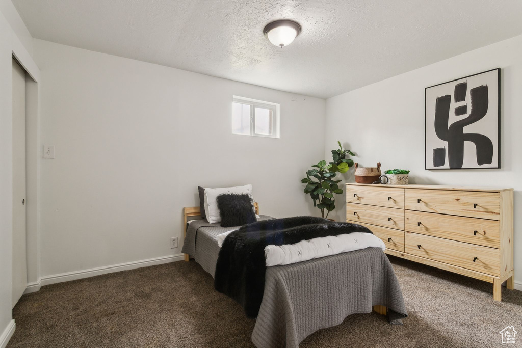 Bedroom with dark colored carpet, a textured ceiling, and baseboards