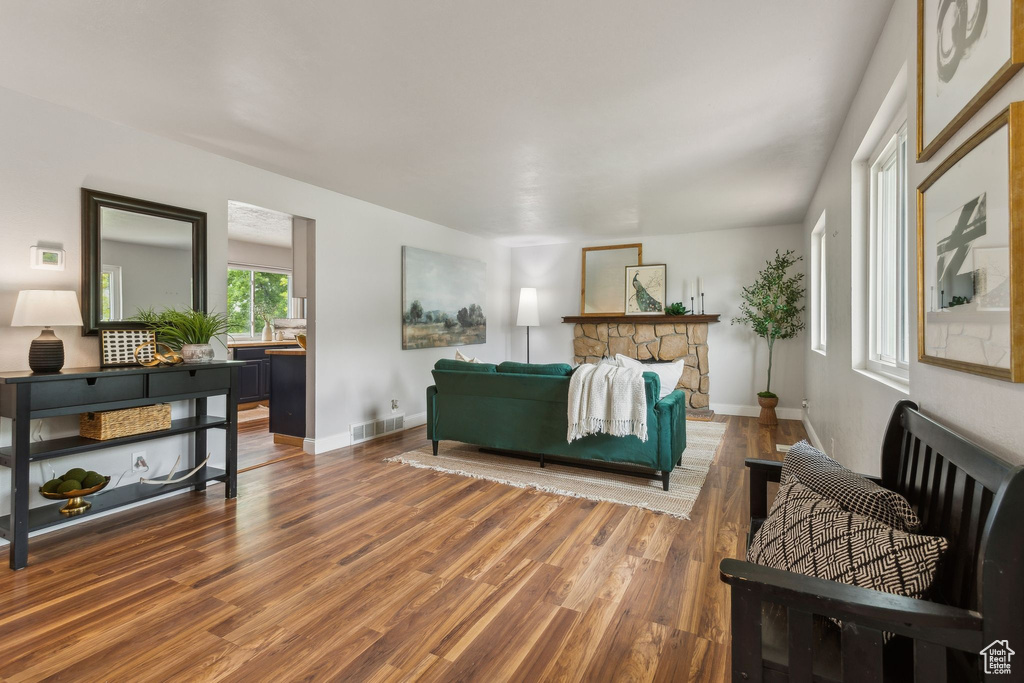 Living room with wood finished floors, baseboards, and a stone fireplace