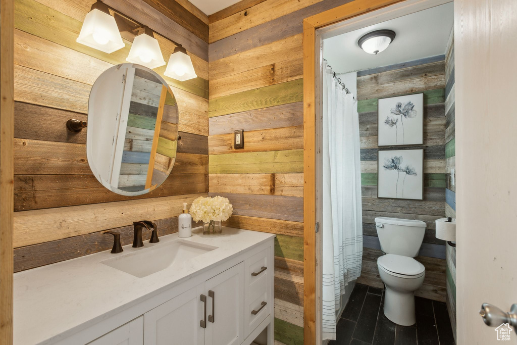 Bathroom with toilet, vanity, and wooden walls
