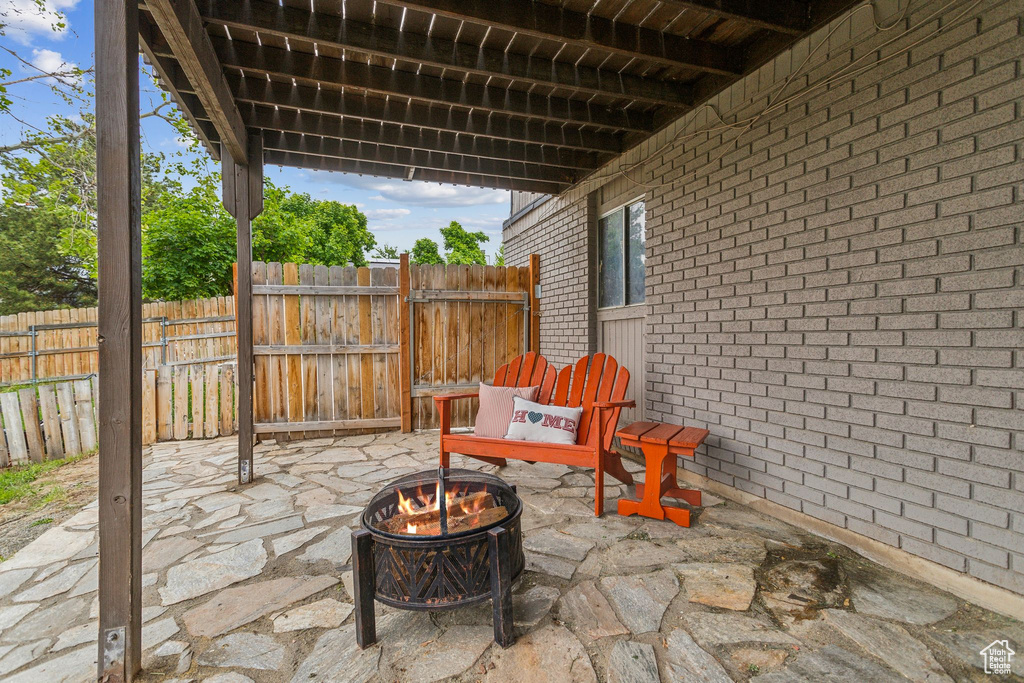 View of patio with an outdoor fire pit and fence