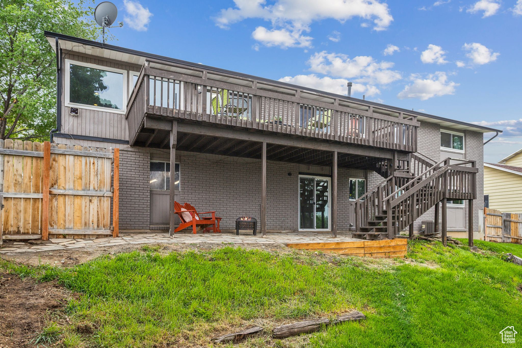 Rear view of property featuring brick siding, a wooden deck, and stairway