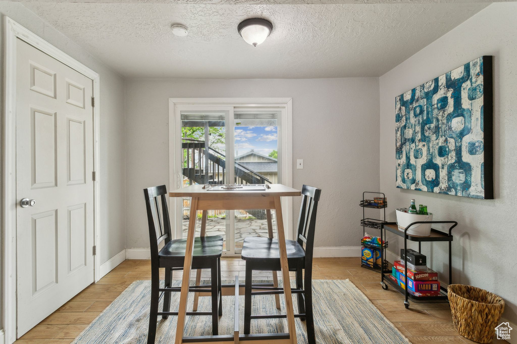 Dining space featuring a textured ceiling, light wood-style flooring, and baseboards