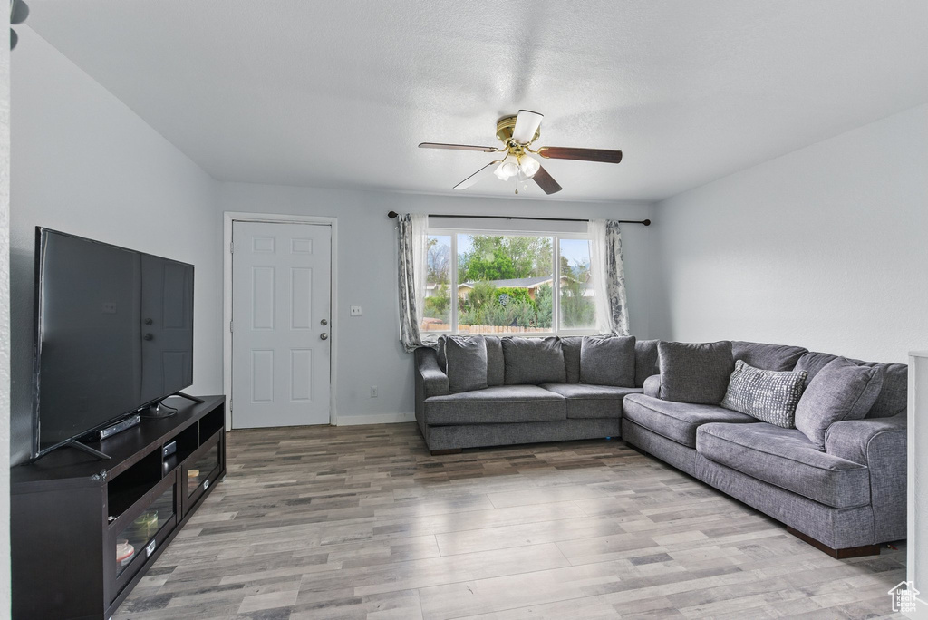Living area with ceiling fan, light wood finished floors, and baseboards