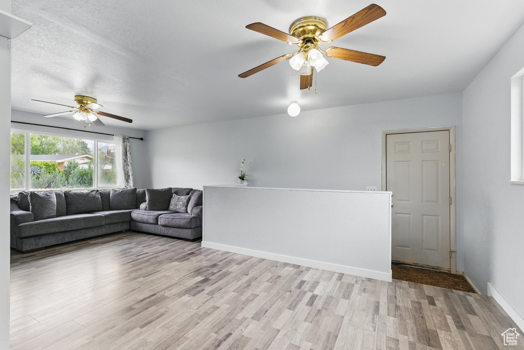 Living room featuring a ceiling fan, light wood-style floors, and baseboards