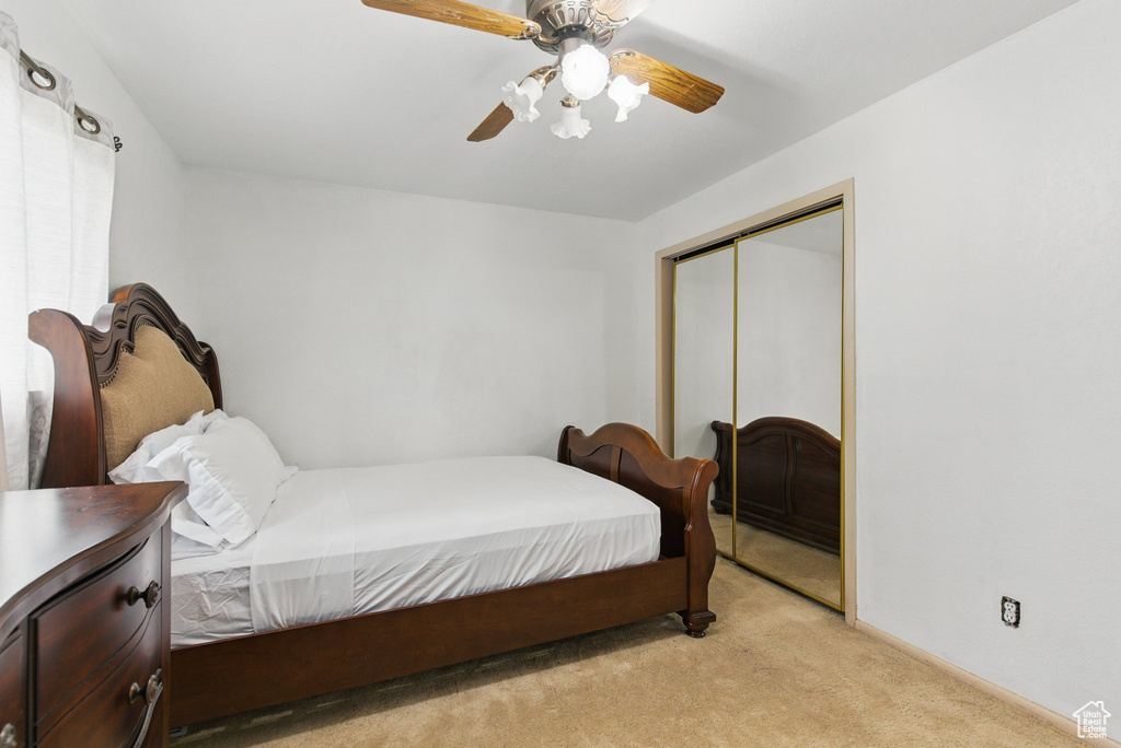 Bedroom featuring light carpet, a closet, ceiling fan, and baseboards