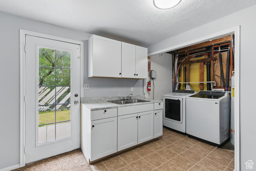 Washroom featuring washing machine and dryer, cabinet space, and a textured ceiling