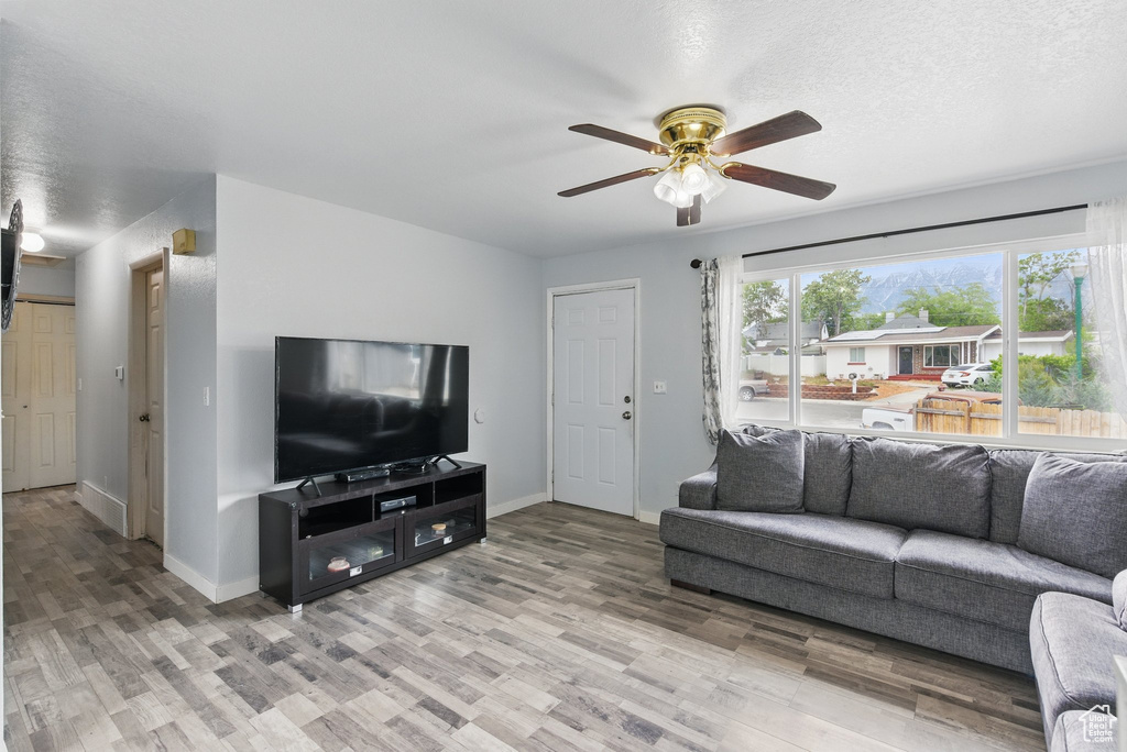 Living room with ceiling fan, baseboards, and light wood-style floors