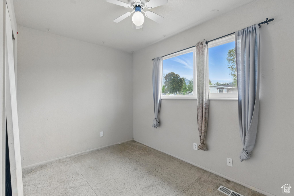 Empty room with ceiling fan, carpet floors, and baseboards