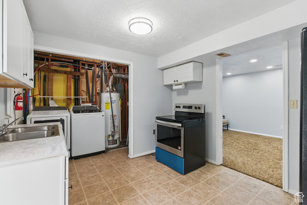 Kitchen featuring stainless steel range with electric cooktop, water heater, washer and dryer, white cabinetry, and a sink