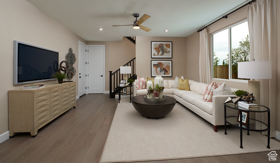 Living area featuring wood finished floors, stairway, baseboards, recessed lighting, and ceiling fan