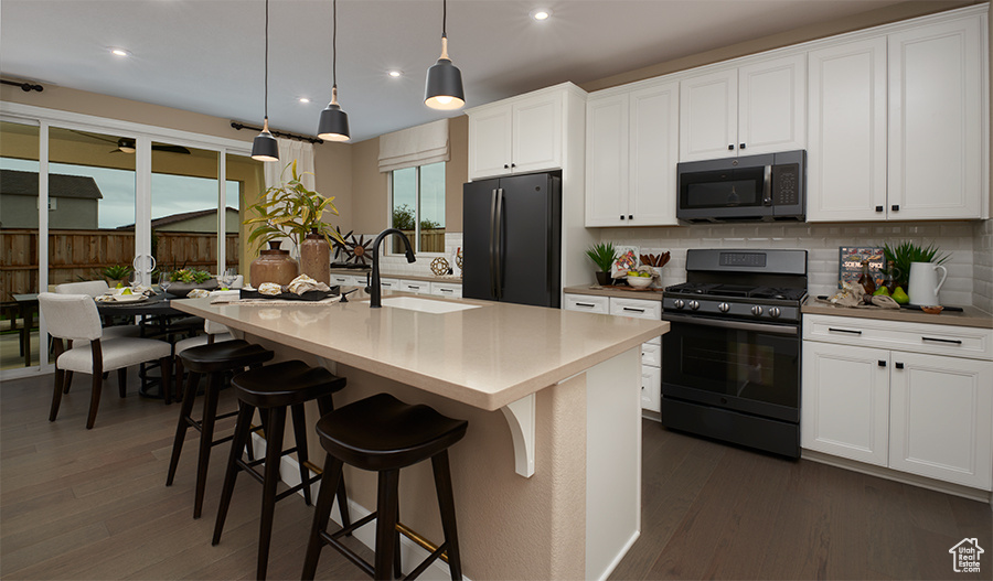 Kitchen featuring stainless steel microwave, range with gas stovetop, freestanding refrigerator, tasteful backsplash, and a sink