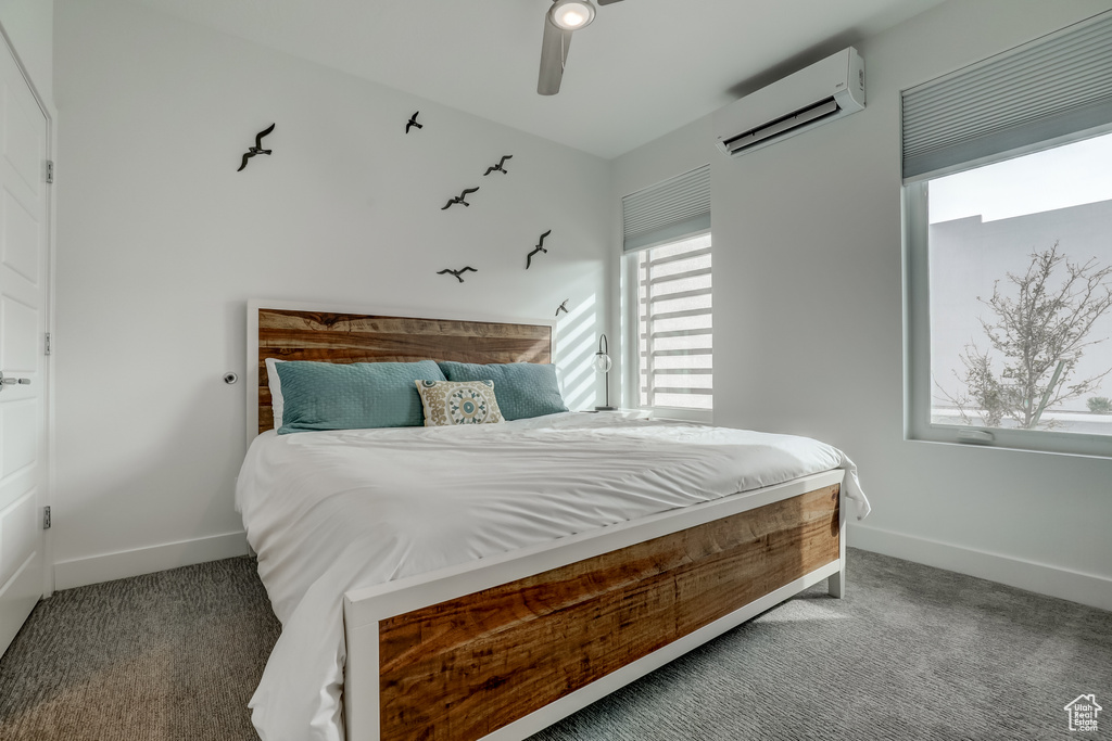 Carpeted bedroom with an AC wall unit, baseboards, and a ceiling fan
