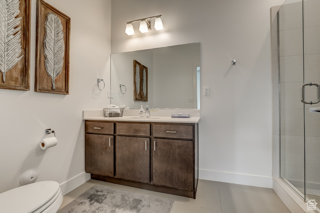 Bathroom featuring baseboards, a shower stall, toilet, and vanity