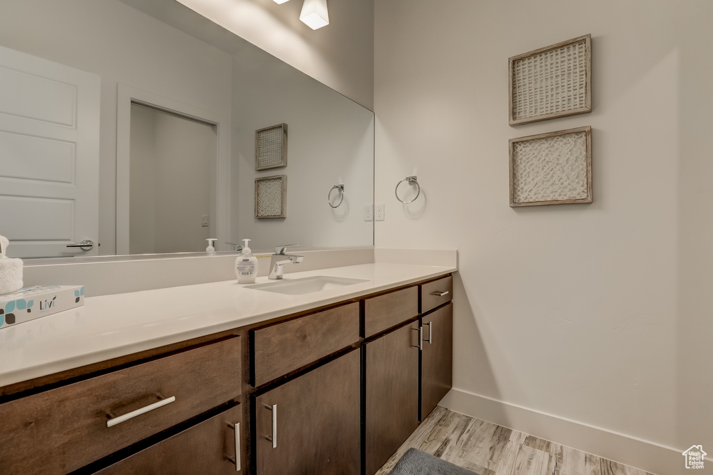 Bathroom featuring vanity, wood finished floors, and baseboards