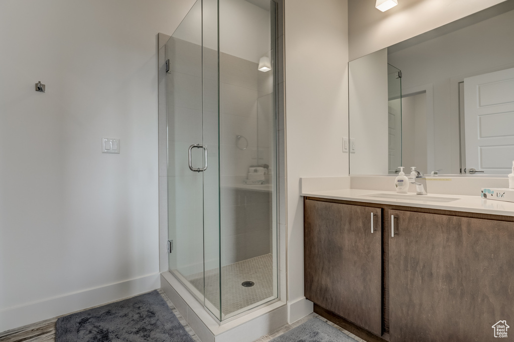Bathroom featuring a stall shower, vanity, and baseboards