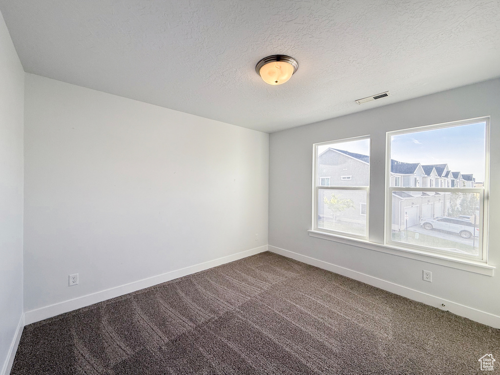 Carpeted spare room with baseboards and a textured ceiling