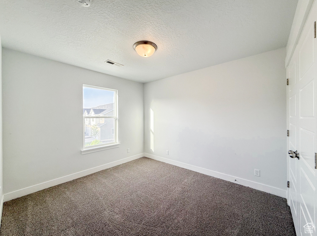 Carpeted empty room with baseboards and a textured ceiling