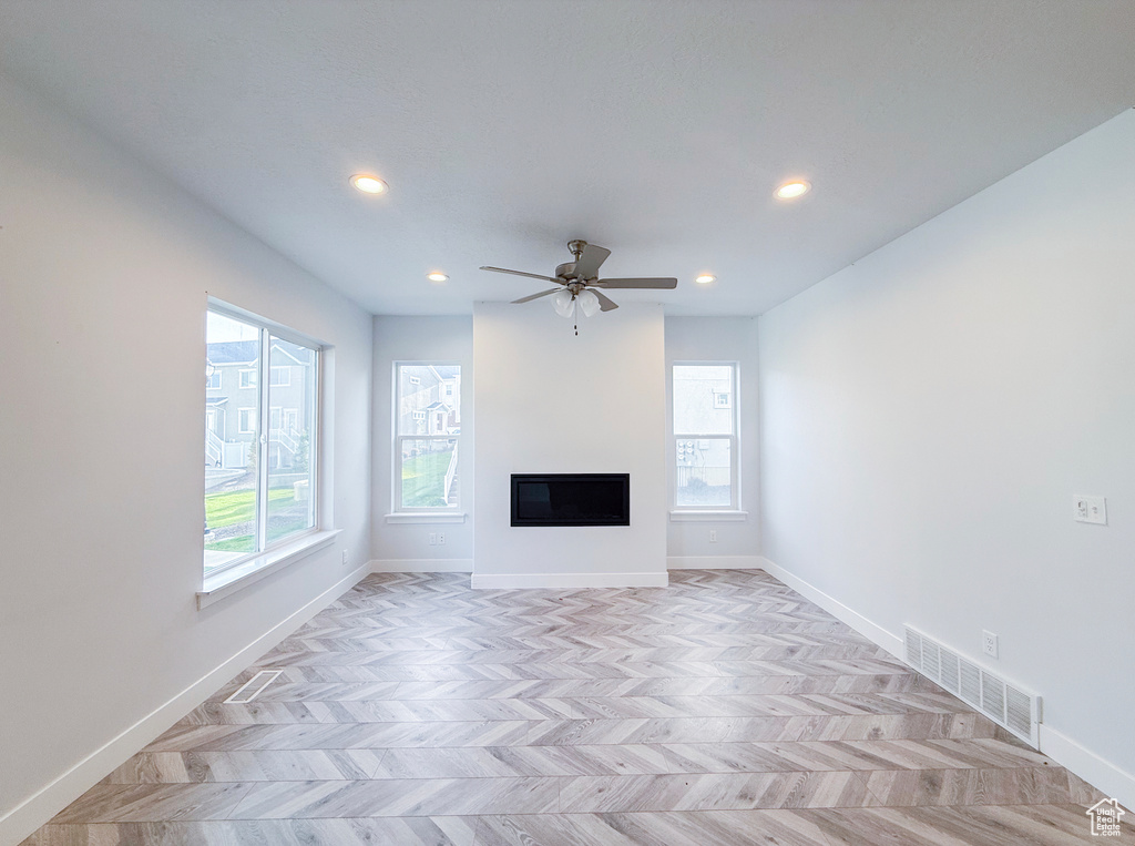 Unfurnished living room with healthy amount of natural light, baseboards, recessed lighting, and a glass covered fireplace