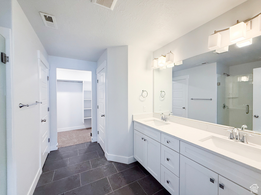 Bathroom featuring a stall shower, baseboards, double vanity, tile patterned floors, and a textured ceiling