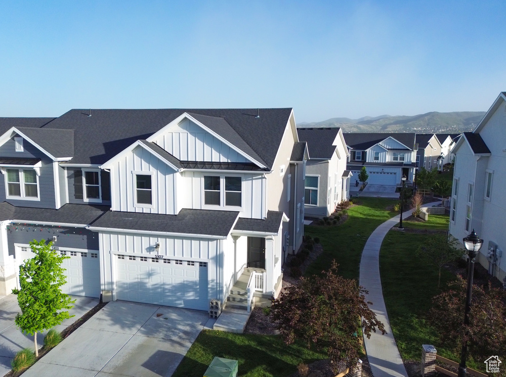 View of front of house with board and batten siding, a garage, a residential view, driveway, and a shingled roof