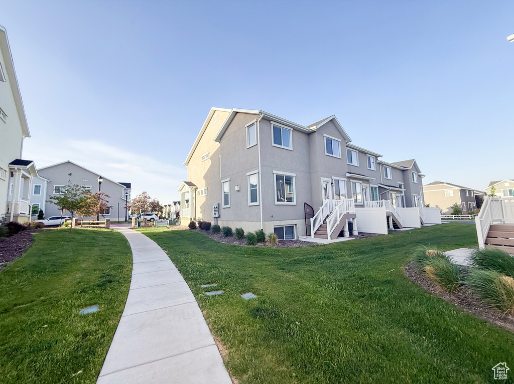 View of property exterior with a residential view, a lawn, stairway, and stucco siding