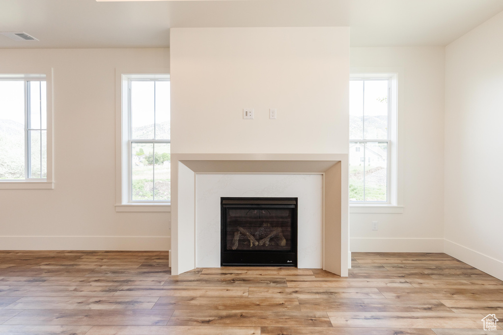 Unfurnished living room with wood finished floors, baseboards, and a glass covered fireplace