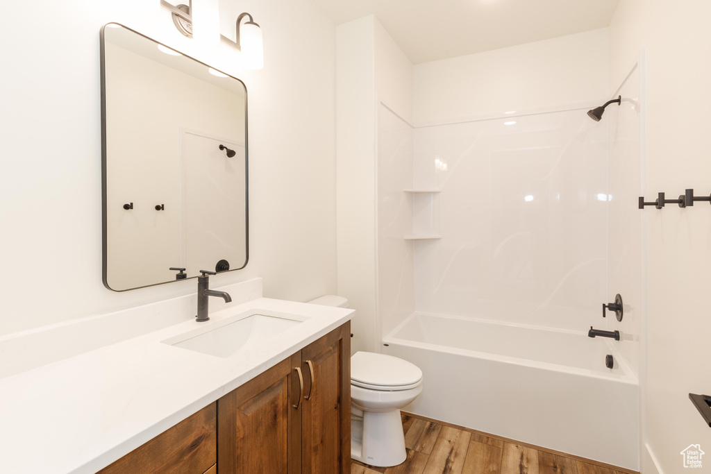 Full bathroom featuring toilet, wood finished floors, vanity, and tub / shower combination