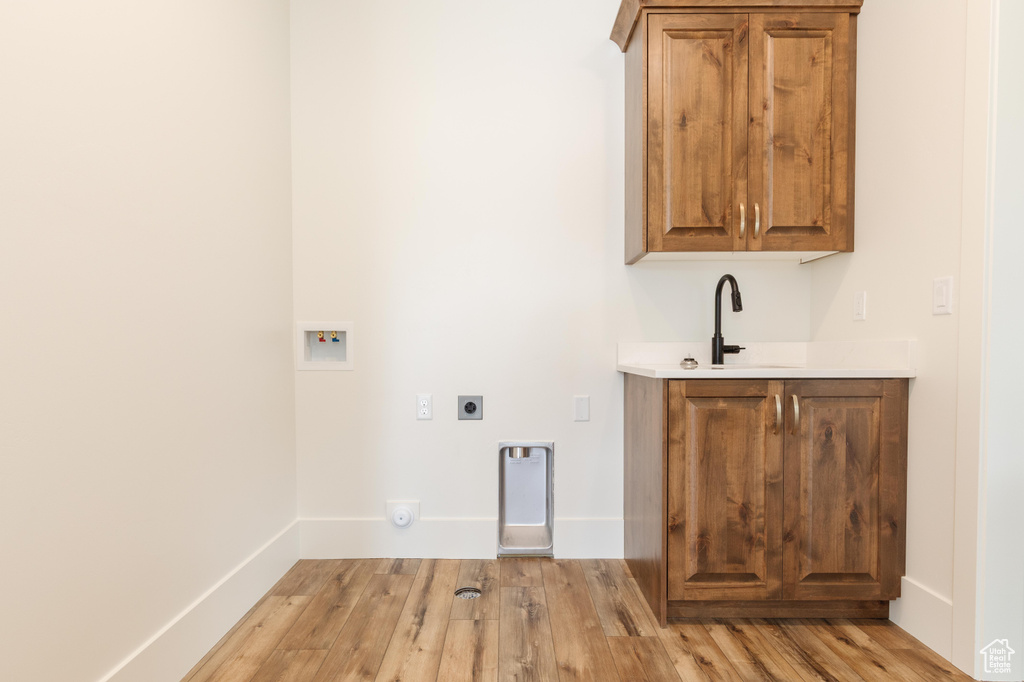 Laundry room with washer hookup, electric dryer hookup, cabinet space, light wood-style flooring, and baseboards