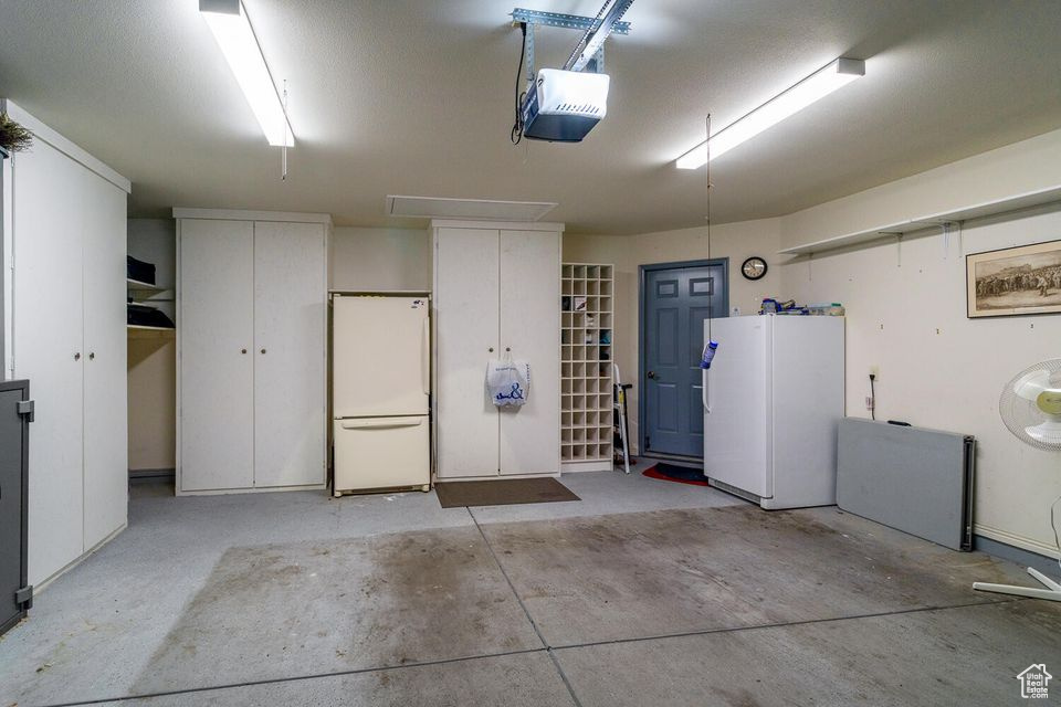 Garage featuring freestanding refrigerator and a garage door opener