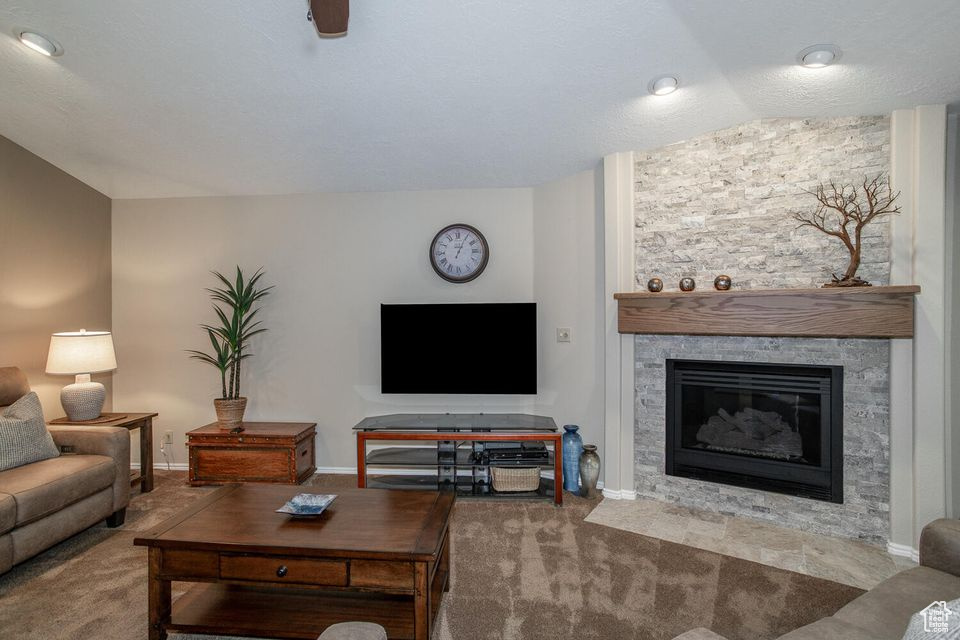 Carpeted living area with a fireplace, lofted ceiling, and baseboards