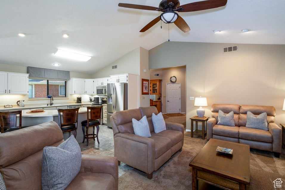 Living room with lofted ceiling, light carpet, and a ceiling fan