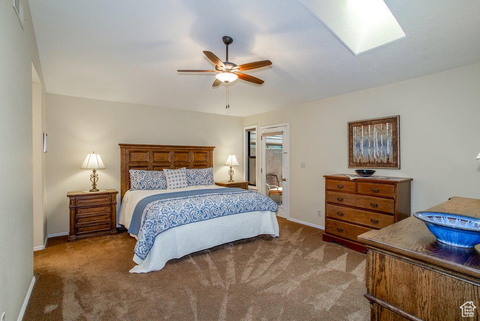 Carpeted bedroom with baseboards, a skylight, and a ceiling fan