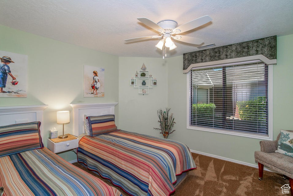 Bedroom featuring carpet floors, baseboards, ceiling fan, and a textured ceiling