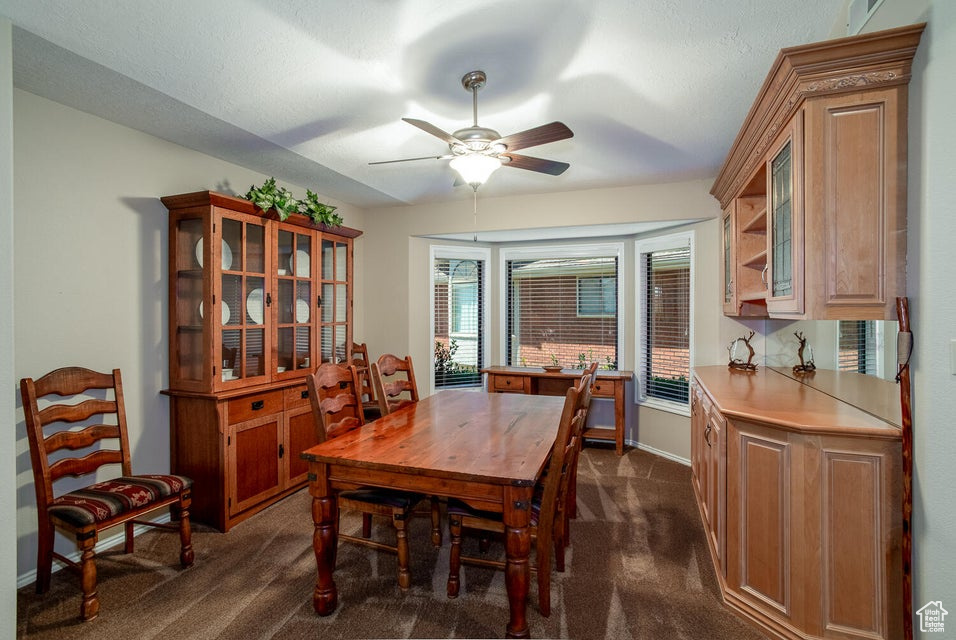 Dining room with dark carpet, a ceiling fan, and baseboards