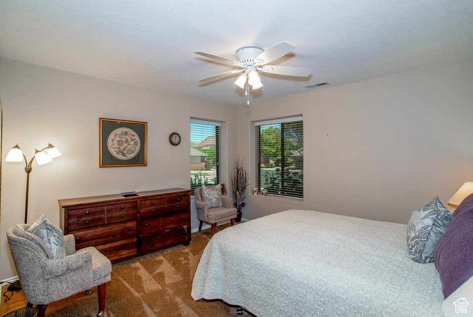 Carpeted bedroom featuring a ceiling fan