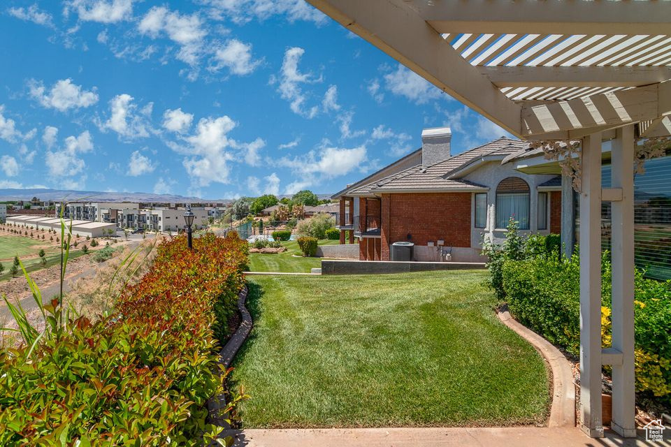 View of grassy yard with a pergola and central AC