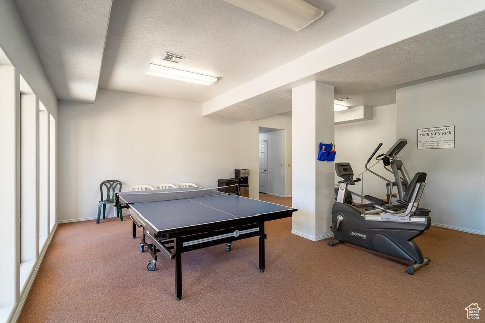 Playroom with a textured ceiling, carpet flooring, and baseboards