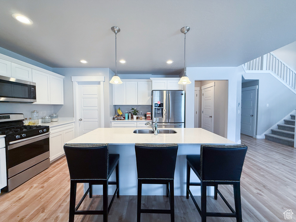 Kitchen featuring appliances with stainless steel finishes, a breakfast bar area, light countertops, a sink, and recessed lighting